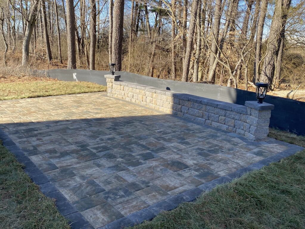 A new stone patio with a short wall.